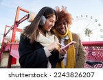Mixed race young couple in winter clothes with cell phones outdoor. Excited students using their technological devices. Concept of young enterprising, friendly, mobile app, hipster millennial