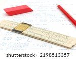 Small photo of Symbol for technical calculation with an old vintage slide rule lying on a paper with mathematical calculations together with a pencil and eraser.