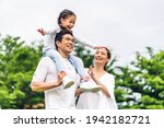 Small photo of Portrait of enjoy happy love asian family father and mother holding cute little asian girl child smiling playing and having fun moments good time in summer park at home