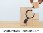 Small photo of Identify and clarify concept. Market and customer target and focusing. Hand hold the wooden cubes with magnifying glass and cropped object symbols on white background with copy space. SEO concept.