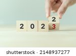 Small photo of Beginning and start of the new year 2023. Preparation for happy new year ,new life, new business, plan, goals, strategy concept. Hand flips wooden cubes with 2022 to 2023 on smart background.