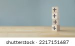 Small photo of Plus sign in wooden cubes stacking. Positive things; additional, added value, benefits, improve, develop, growth mindset, positive thinking, motivation, increase, opportunities, and emerging market.