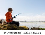 Small photo of the boy is trying to pull the fish out of the river with the help of a fishing rod, his fishing rod bends from the fish