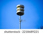 Small photo of Pole with Dutch acoustic air alarm system also known as air raid siren alert and also known as luchtalarm in Dutch with clear blue sky in Holland used to warn public for example during war or attack