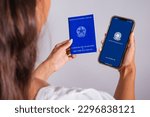 Small photo of hands holding workbook and smartphone. Formal work applications, job vacancies. English translation is (Employment Card and Social Security)