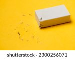 Small photo of White eraser on a yellow background. Rubbish from erasure.