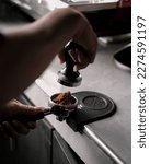 Small photo of barista tempering ground coffee into espresso pitcher