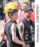 Small photo of Blackpool, Lancashire, UK August 6 2022 A young girl with facial piercings and a bright yellow punk quiff smiles at friends during the Blackpool Rebellion Punk Festival