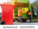 Two garbage men working together on emptying dustbins for trash removal with truck loading=