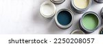 Small photo of Tiny sample paint cans during house renovation, process of choosing paint for the walls, different green and beige colors, color charts on background