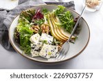 Small photo of Healthy Salad made from Green Salad Leaves, Rocket Salad, Slices of Fresh Pears, pieces of Blue Cheese, Walnuts and Sesame Seeds.