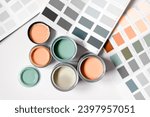 Small photo of Tiny sample paint cans during house renovation, process of choosing paint for the walls, Peach Fuzz color of the year 2024, color charts on background