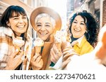 Small photo of Group of smiling mature women eating ice cream cone outside in a sunny day - Three older friends girls take a happy selfie while walking at city - Concept about elderly people, food and joyful weekend