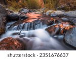 Small photo of Oak Creek rushes through volcanic boulders with sunset light glimmering on its surface