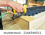 Small photo of Stapling elastic band with a yellow pneumatic stapler. Furniture manufacture shot. Selective focus