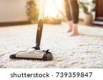 Young woman using a vacuum cleaner while cleaning carpet in the house.