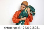 Small photo of Asian Muslim man gesturing hugging a bolster pillow on a white background