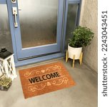 Small photo of Designer Welcome Entry Doormat Placed on Solid Brick Floor Outside Entry Door with Plants