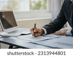 Small photo of Close up of businessman working at office with laptop, tablet and graph datasheets on his desk