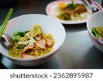 Small photo of Wanton mee served in a bowl with condiments
