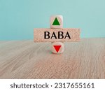 BABA price symbol. A brick block with arrow symbolizing that Alibaba Group Holding index price are going down or up. Beautiful wooden table blue background. Business and BAB price concept. Copy space