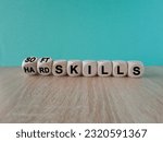 Small photo of Hard skills versus soft skills. Dice form the expressions hard skills and so ft skills. Beautiful blue background. Wooden table, Business concept. Copy space.