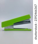 Small photo of green stapler on white vertical background. Paper green stapler on isolated white background.