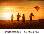 Children launch a kite in the field at sunset