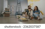 Small photo of Cheerful young couple in the morning at home. Newlywed caucasian couple are relaxing during renovation of their new home and positively smiling - new life, mortgage concept