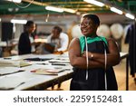 african female business woman textile industry wearing a green shirt with black apron measuring tape with arms folded