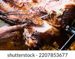 Small photo of Chef Hands cutting whole grilled pork for steaks with knife. Pig grilled traditional coal and fire. The little piglet is roasted whole on an open fire. Pig on the spit