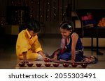 Small photo of Indian kids decorating with oil lamps for Diwali festival