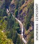 Small photo of Train passes through a mountain. Freight train on a railway line on a mountain pass. Train passing through the woods, aerial view. Cargo train with fuel passing through the forest top view, nobody