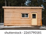 Small wooden cabin house in the evening. Exterior design. Small house for vacation. Log cabin in a forest in the winter. Travel photo, nobody