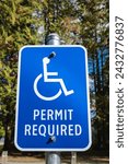 Small photo of Handicap parking sign with trees background. Handicapped parking spot. Blue handicapped sign. Disabled parking permit sign on pole. Reserved parking lot for mobility or disable people