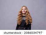 Photo of dreamy cute positive little girl with blond long wavy hair looking blank space wonder smile in black clothes isolated on light gray background