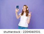 Happy girl communicates via video communication using a mobile phone on a colored background in the studio, Caucasian girl rejoices in communication