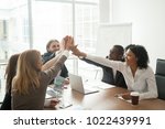 Excited african and caucasian business team giving high five at office meeting motivated by victory, achievement or good work result, multi-ethnic employees group celebrate corporate success together