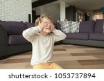 Kid boy playing hide and seek game at home, child closing eyes with hands counting while parents and sister hide behind sofa in living room peeking out, happy family having fun with children concept