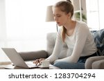 Small photo of Young woman freelancer using laptop working online making notes, focused teen girl studying on computer writing essay, searching job opportunity, preparing research or coursework in internet at home