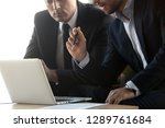 Small photo of Serious businessmen in suits talk work together with laptop, financial advisor consulting convincing client about online investment benefits concept, make business offer with computer, close up view