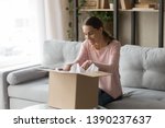 Happy woman sitting on couch at home opening carton box received parcel package from relatives or shopper make order internet website satisfied client, easy and fast service commerce delivery concept