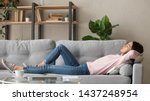 Small photo of Tired young woman lying on cozy couch take nap daydreaming in living room, peaceful girl relax on comfortable sofa with eyes closed sleeping resting at home, female feel fatigue fall asleep