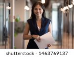 Happy smiling asian businesswoman looking at camera holding papers stand in office hallway, happy confident chinese professional executive satisfied with good career posing in modern office, portrait