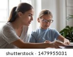 Small photo of Young mother lend support to daughter with homework, babysitter, older sister or private tutor teacher explaining girl in glasses task, teaching pupil school child, help in educational process concept