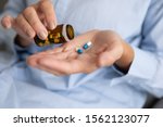 Elderly sick ill woman hold two pills on hand pouring capsules from medication bottle take painkiller supplement medicine, old senior people pharmaceutical healthcare treatment concept, close up view