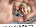Portrait of overjoyed middle-aged 60s retired couple look at camera make heart with hands posing, smiling elderly 50s husband and wife have fun show love and care, elderly relationships concept
