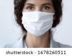 Close up portrait of beautiful 30s young millennial woman cover her face wearing facial medical blue mask, anti-coronavirus COVID-19 pandemic infectious disease outbreak protection, healthcare concept