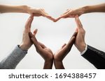 Close up bottom view concept of diverse business people join hands forming heart. Show unity and support, protection of business. Multiracial colleagues involved in team building activity for charity.