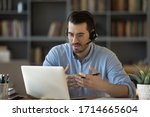 Small photo of Confident man teacher coach wearing headset speaking, holding online lesson, focused student wearing glasses looking at laptop screen, studying, watching webinar training, listening to lecture